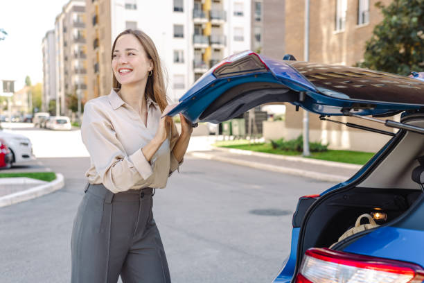 Beautiful elegant woman packed bag inside the trunk and closes the trunk